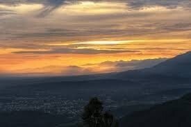 Dramatic monsoon sunset over Doon Valley Dehradun with broken storm clouds and shafts of golden light — September sky